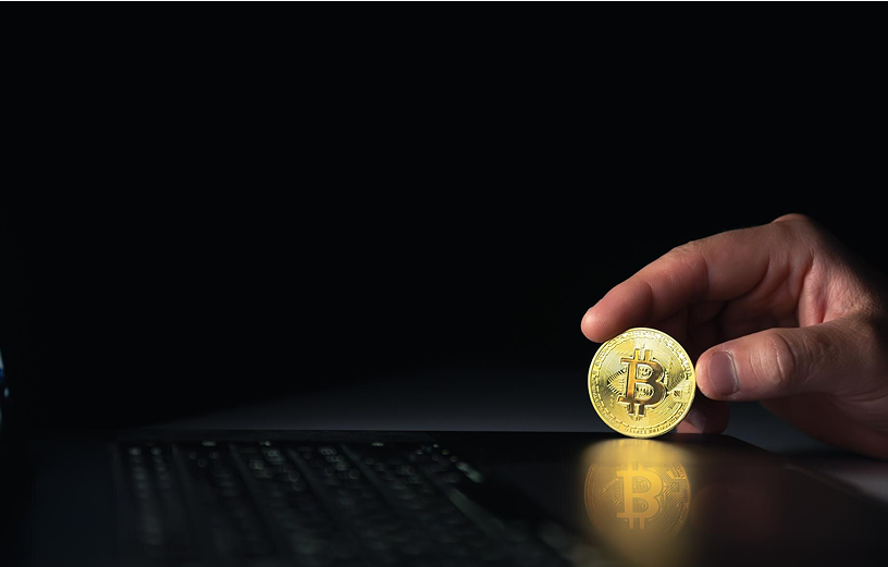 A hand holding a bitcoin, representing online banking and rewards